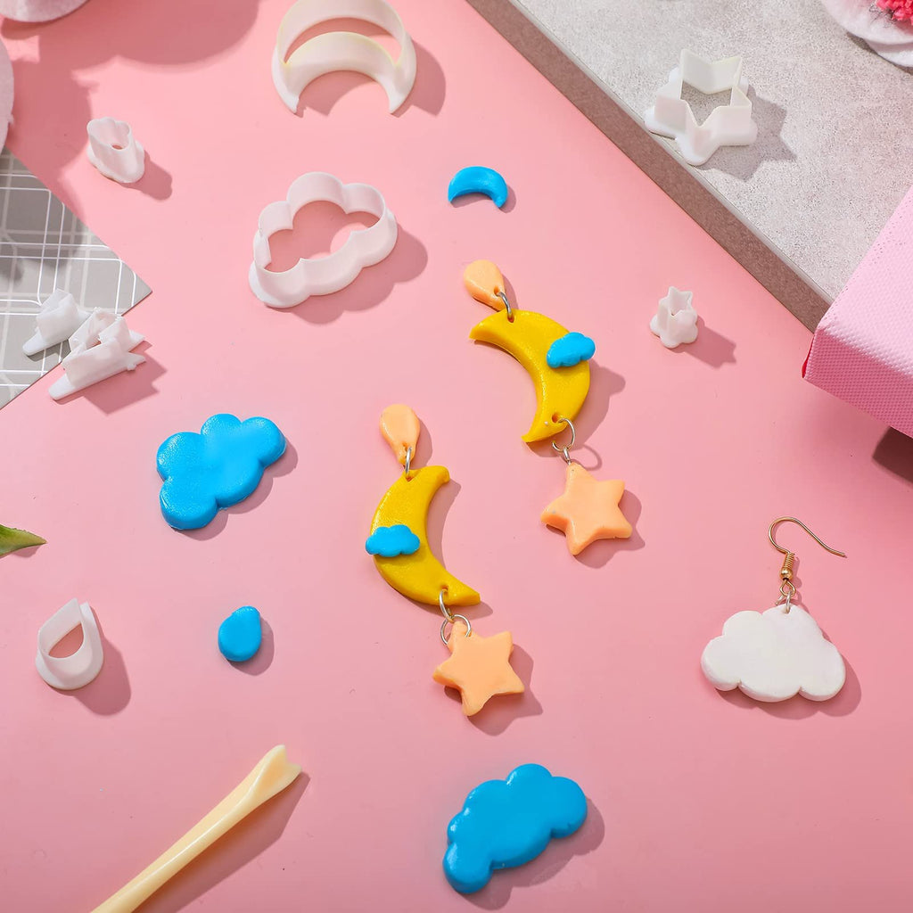 Polymer clay cutters and finished jewelry pieces in cloud, moon, star, and raindrop shapes on a pink background.