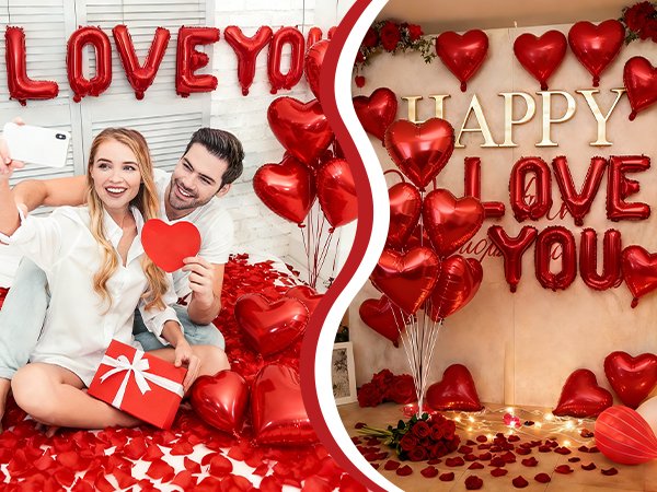Couple taking a selfie with red heart balloons and 'LOVE YOU' foil balloons, surrounded by rose petals and a gift box.