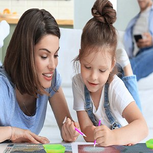 Mother and daughter doing a diamond painting kit together on a table