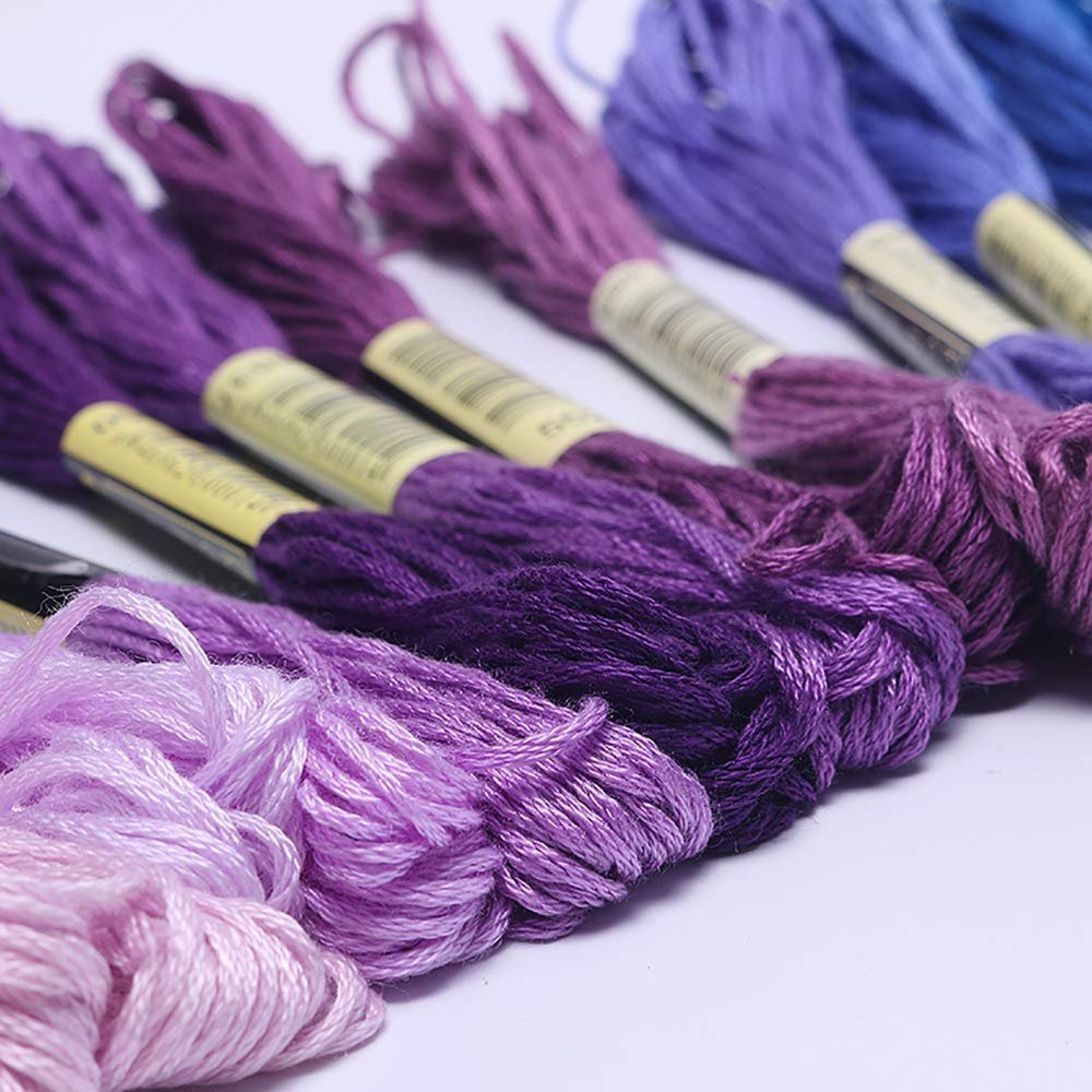 Close-up of purple and blue embroidery floss skeins arranged in a row on a white background.