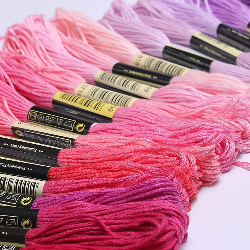 Close-up of pink and purple embroidery floss skeins, showing labels with numbers and text.