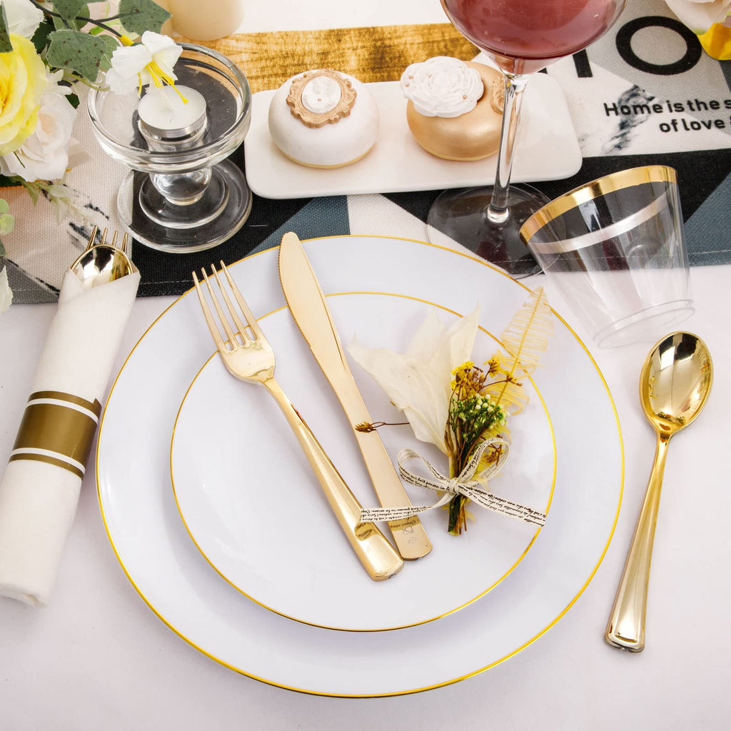 White and gold rim disposable dinnerware set with cutlery, napkin, and cups arranged on a table setting.