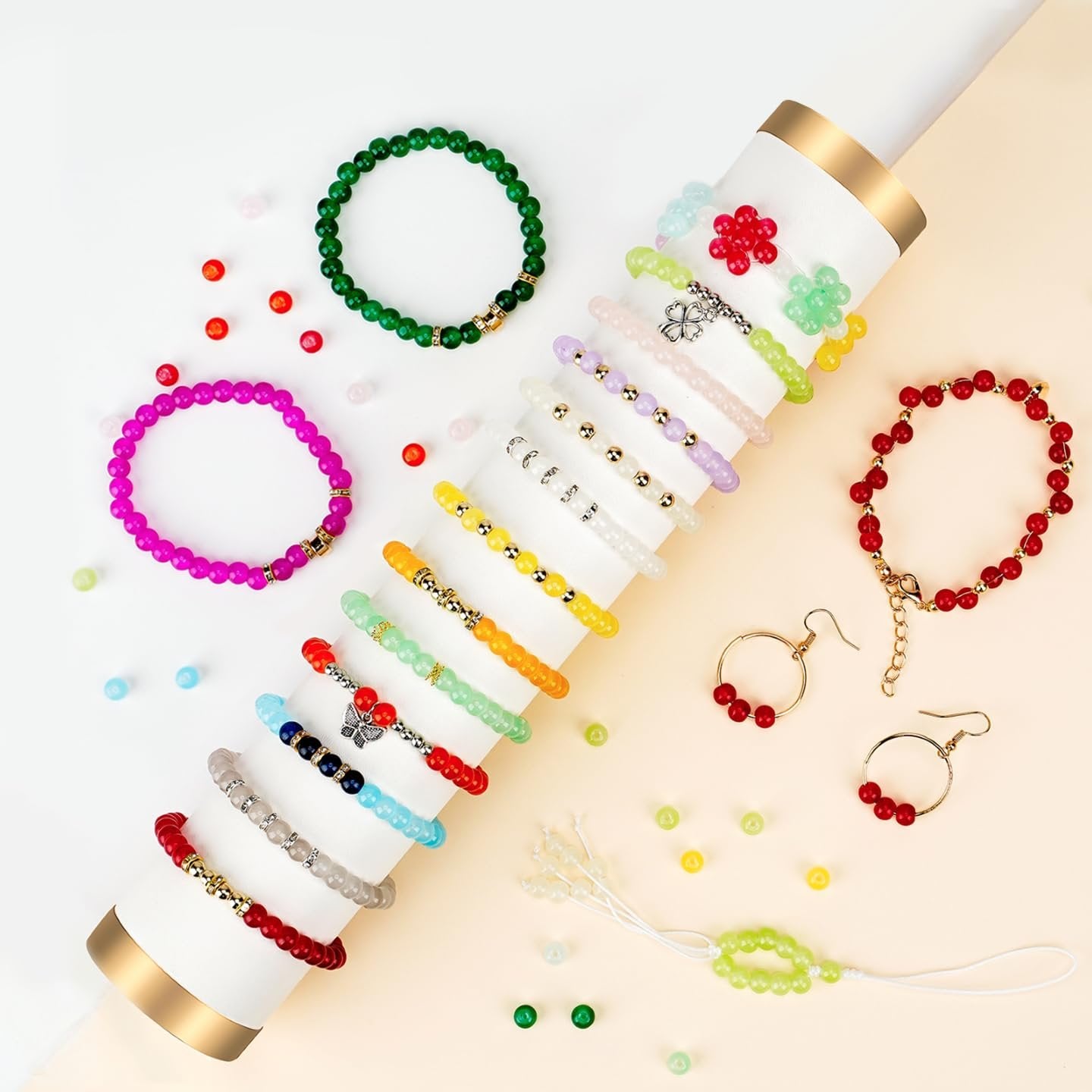 Assortment of colorful glass bead bracelets and earrings arranged on a white and beige surface.