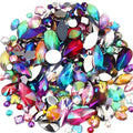 Pile of assorted AB flatback acrylic rhinestones in various shapes and iridescent colors on a white background.