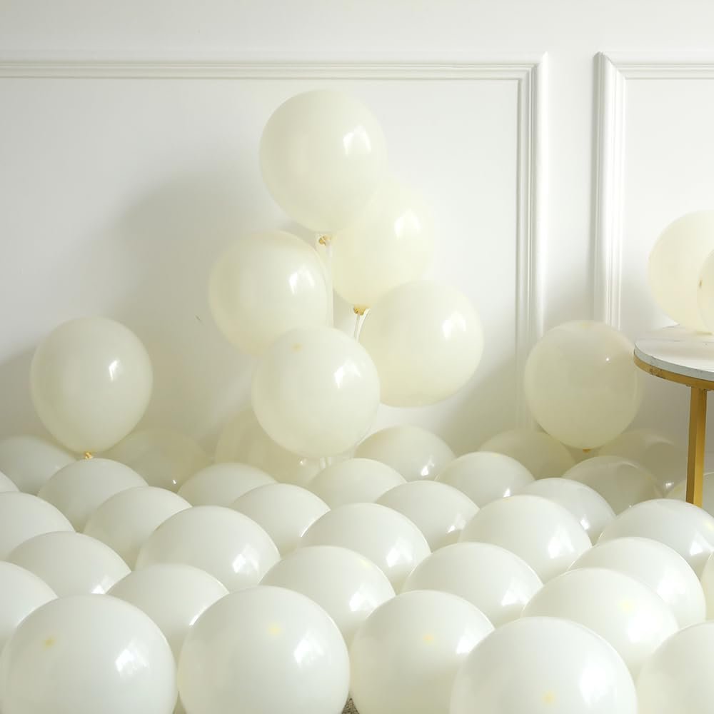 Pile of ivory white latex balloons in various sizes, some inflated and some deflated, against a white wall.