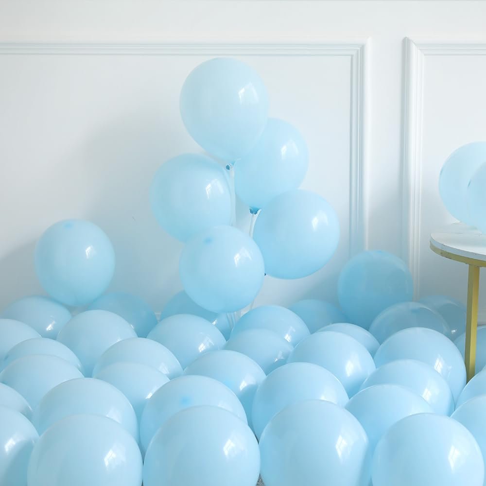 Dusty blue and ivory white balloons piled on the floor, with a small table on the right.
