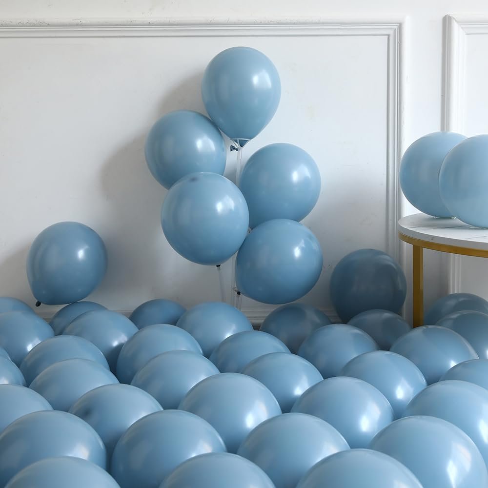 Dusty blue and ivory white balloons scattered on the floor and a table, with some inflated balloons on stands.