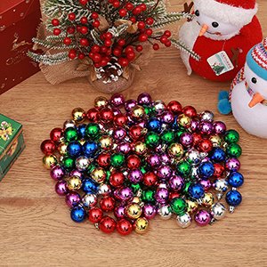 Pile of 144 shatterproof Christmas ball ornaments in red, green, gold, blue, purple, and silver colors on a wooden surface.