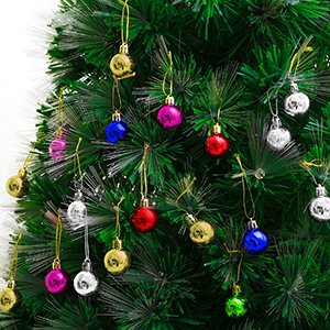 Assortment of small, colorful Christmas ball ornaments hanging on a green artificial Christmas tree branch.