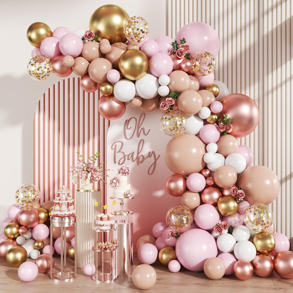 Balloon arch in rose gold, gold, white, and nude tones with confetti balloons, flowers, and a cake display.