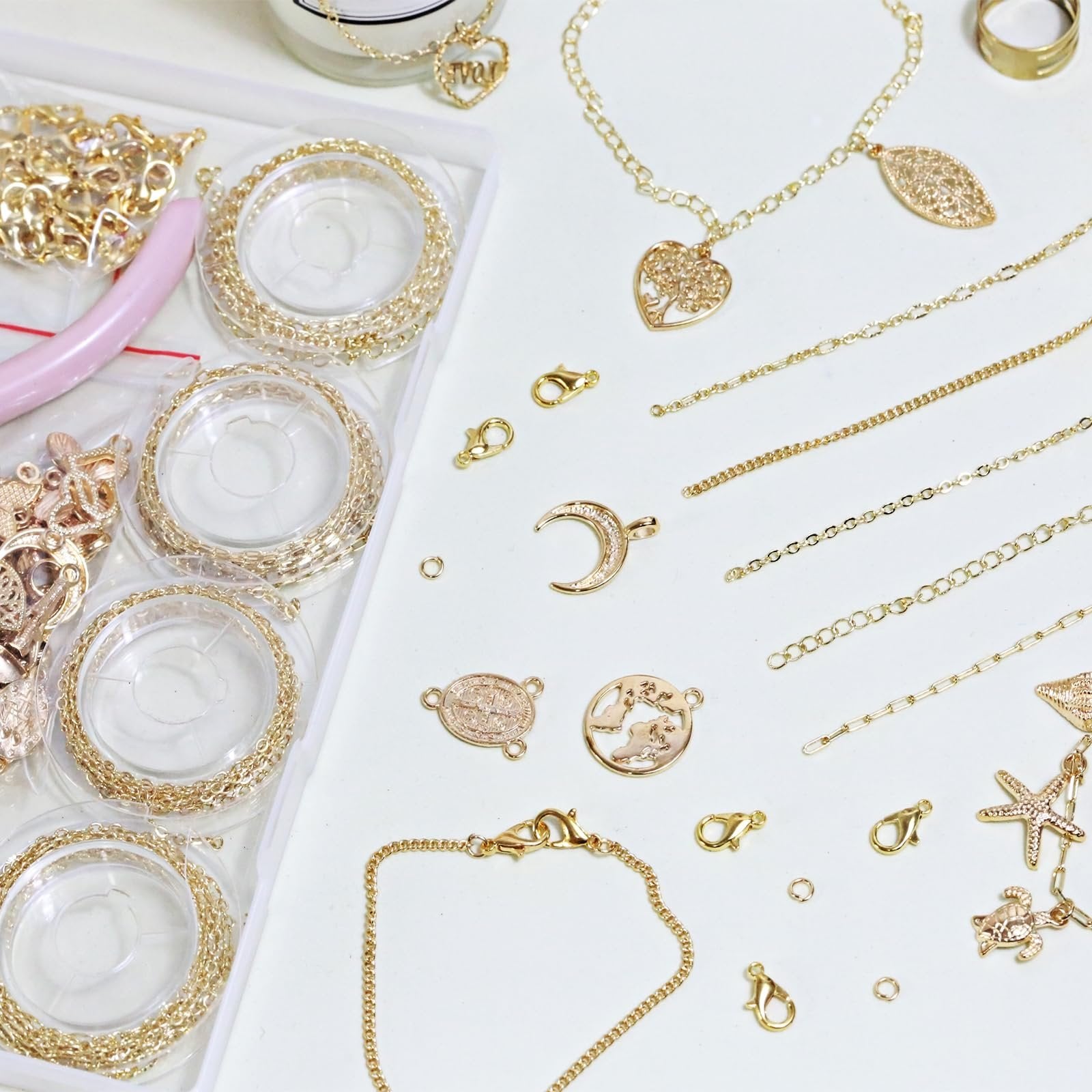 Gold-tone jewelry making kit components including chains, pendants, clasps, jump rings, and pliers laid out on a white surface.