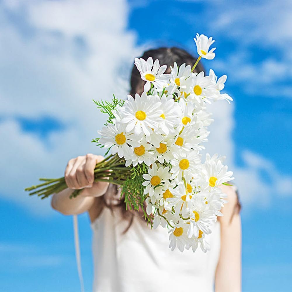 Woman holding a bouquet of white daisies against a blue sky with clouds