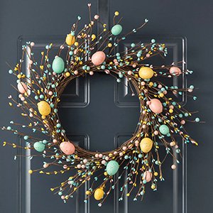 Easter wreath with pastel eggs and berries hanging on a dark gray door