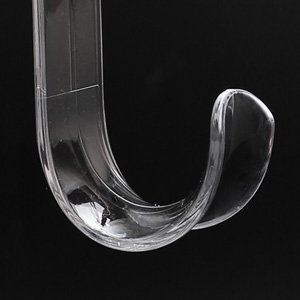 Close-up of a clear acrylic over-the-door wreath hanger hook against a black background.