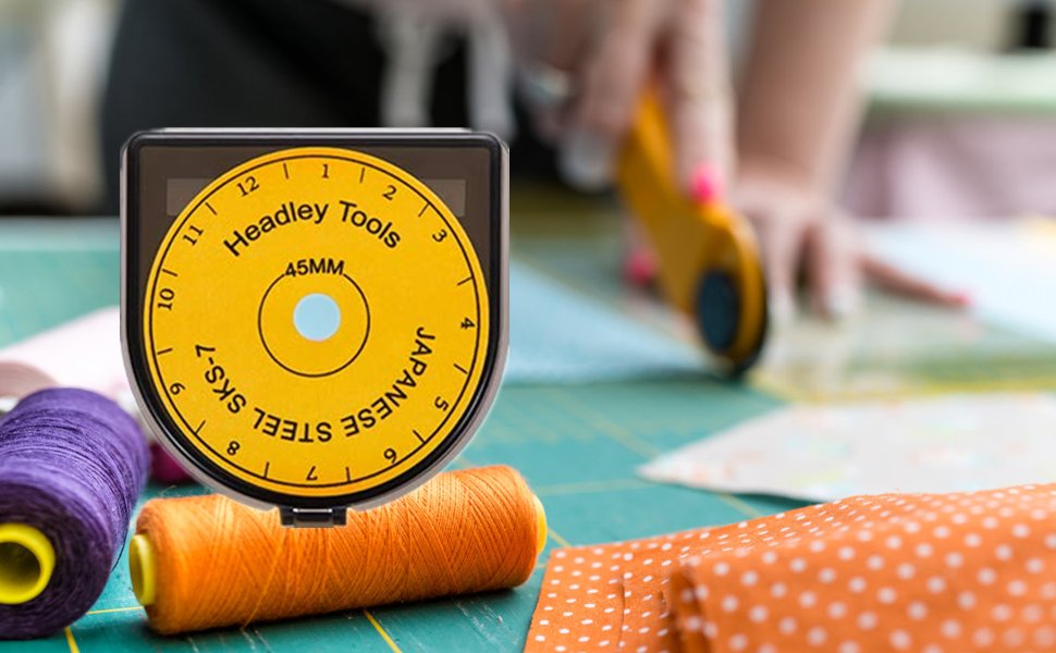 Rotary cutter blades in storage case with spools of thread and fabric, person cutting fabric in background