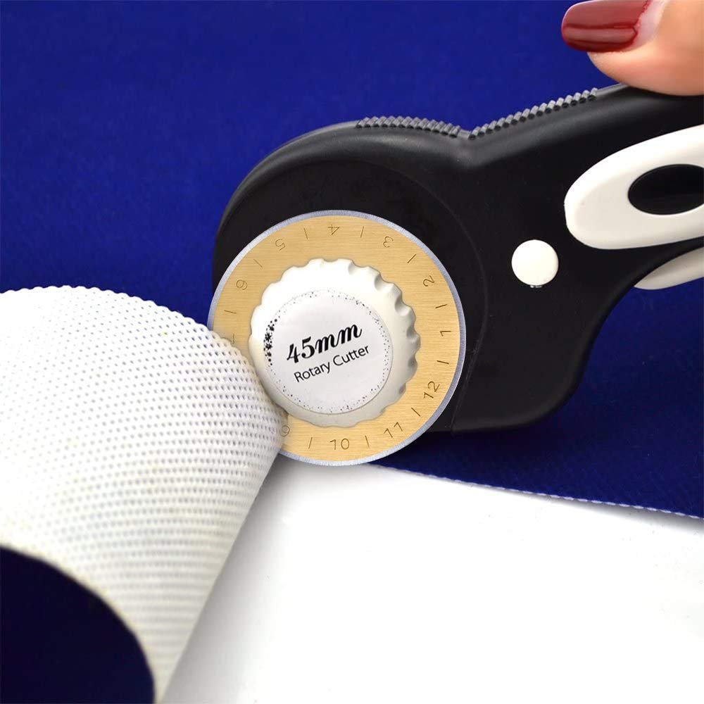 Close-up of a 45mm rotary cutter slicing through white textured fabric on a blue background.
