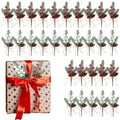 Artificial holly berry picks with red berries, white berries, pinecones, and pine needles arranged on a wrapped gift and in rows.