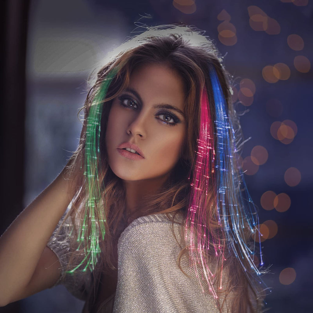 Woman with LED fiber optic hair extensions in green, pink, and blue, with bokeh lights in the background.