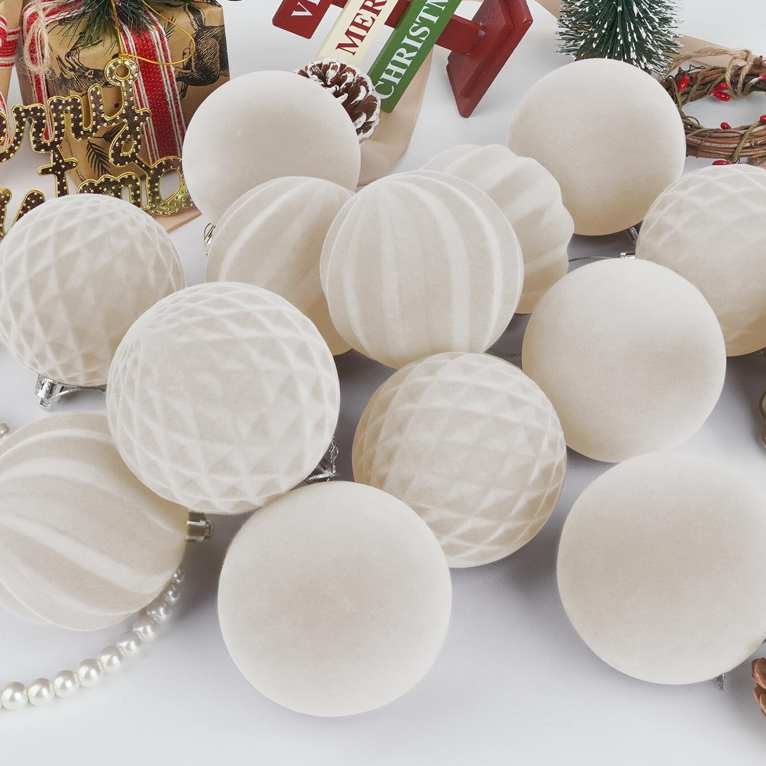 Set of beige flocked Christmas ball ornaments with various textures, arranged with holiday decor elements.