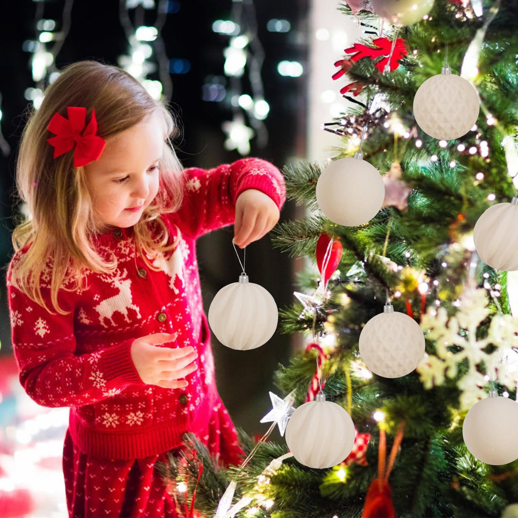 Young girl in a red sweater decorating a Christmas tree with beige flocked ornaments