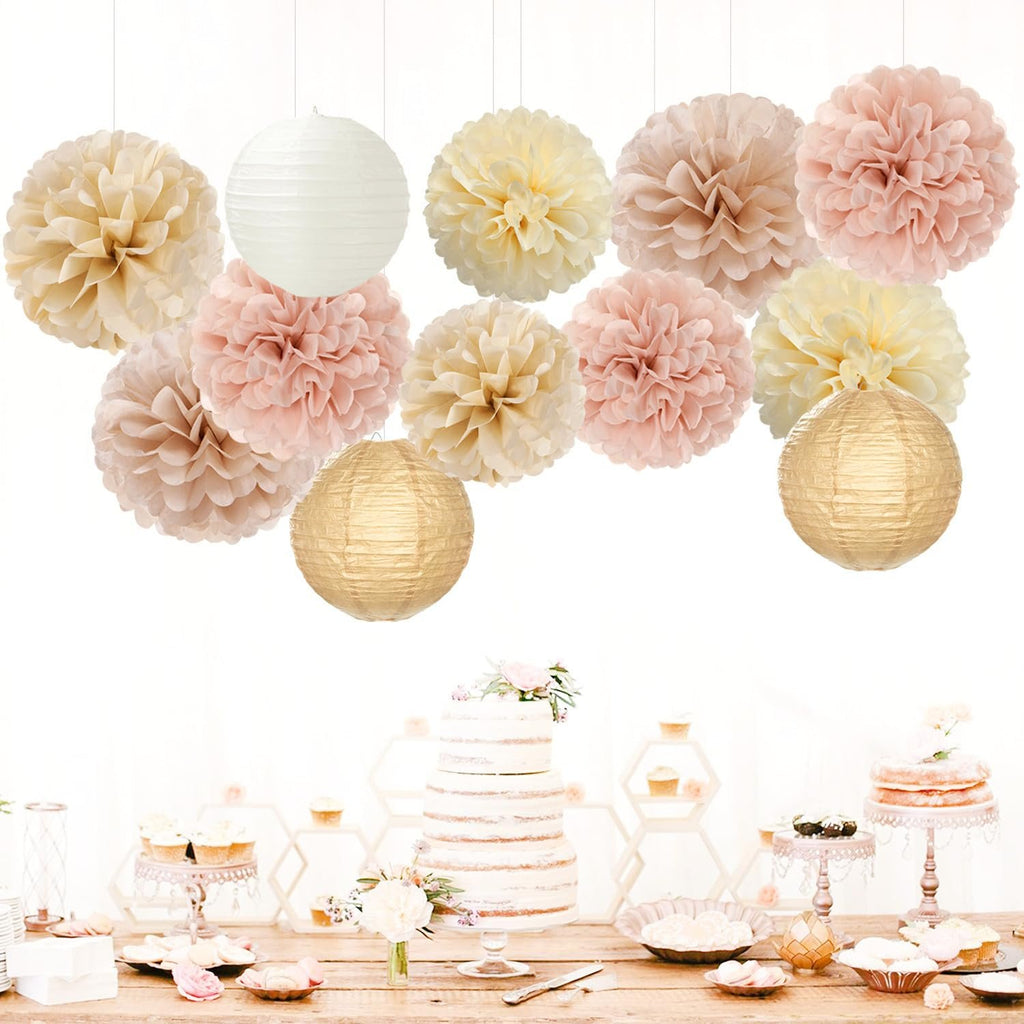 Party decorations including tissue pom poms and paper lanterns displayed above a dessert table with cakes and cupcakes.