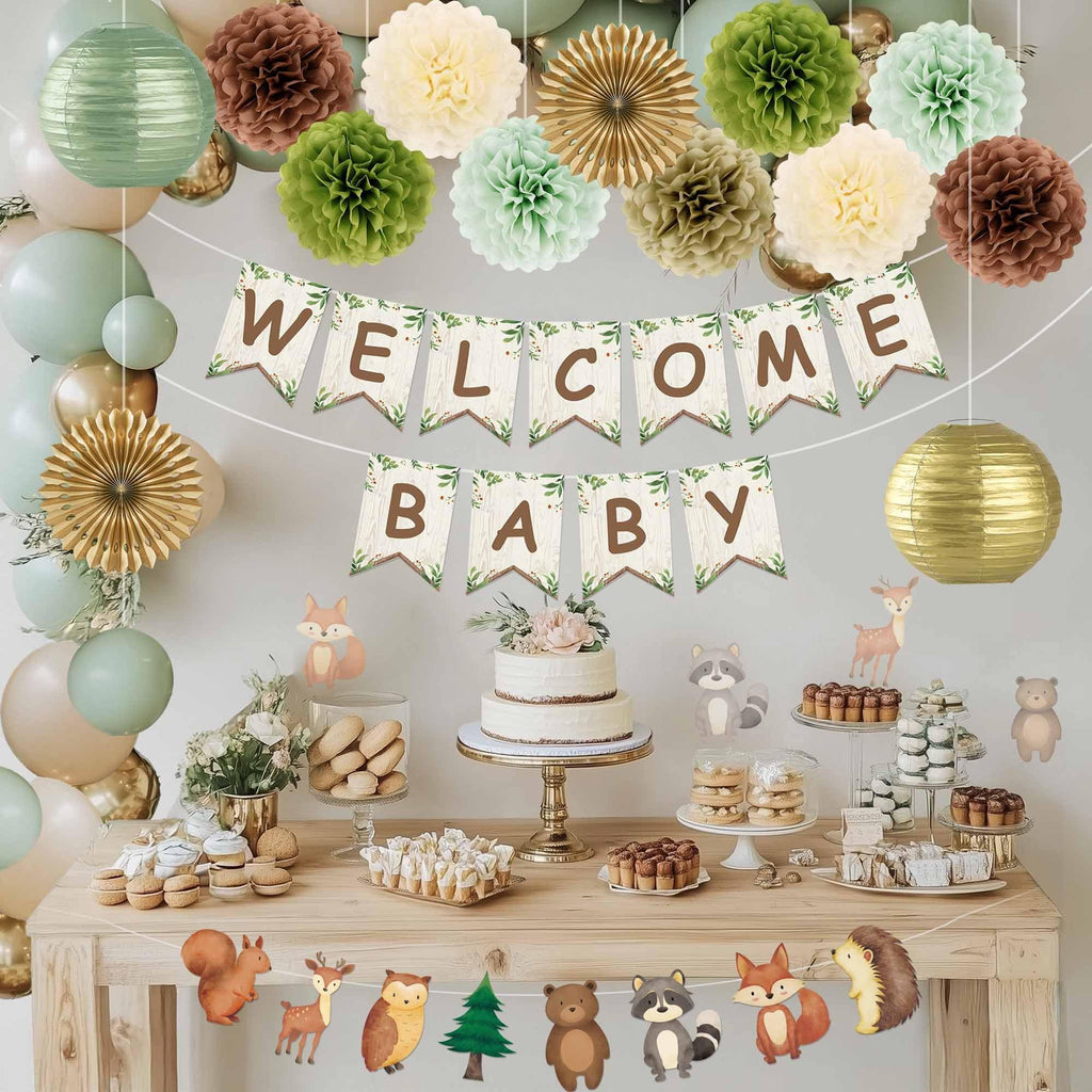 Woodland baby shower decorations including a 'Welcome Baby' banner, pom poms, paper lanterns, balloons, and a dessert table.
