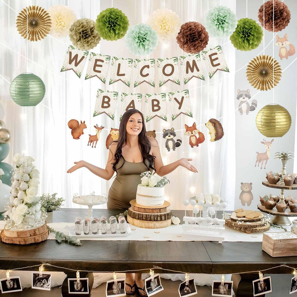 Pregnant woman at a woodland baby shower with cake and decorations, including a 'Welcome Baby' banner and animal cutouts.