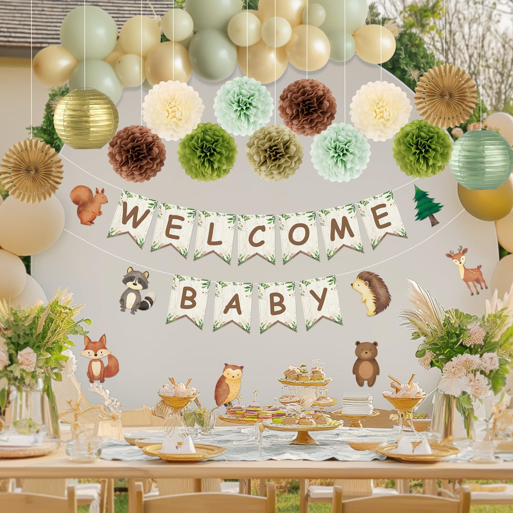 Woodland baby shower decorations including balloons, pom poms, paper lanterns, fans, and a 'WELCOME BABY' banner with animal cutouts.