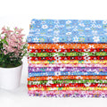 Stack of 15 colorful floral fabric squares with a potted pink plant on the left.