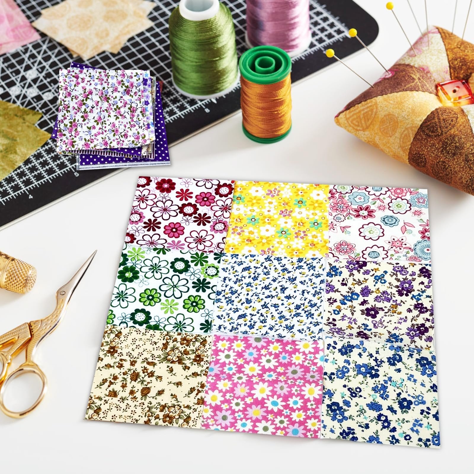 Stack of pre-cut fabric squares with abstract floral patterns, surrounded by sewing supplies like thread spools and scissors.
