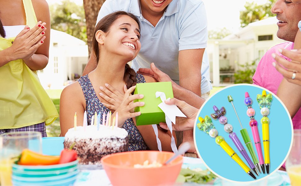 Family celebrating a birthday outdoors with a cake and gifts, with a circular inset showing colorful beadable pens.