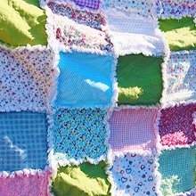 Close-up of a colorful patchwork quilt made of pre-cut fabric squares with frayed edges.