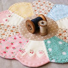 Flower-shaped quilt with two spools of thread in the center, close-up shot.