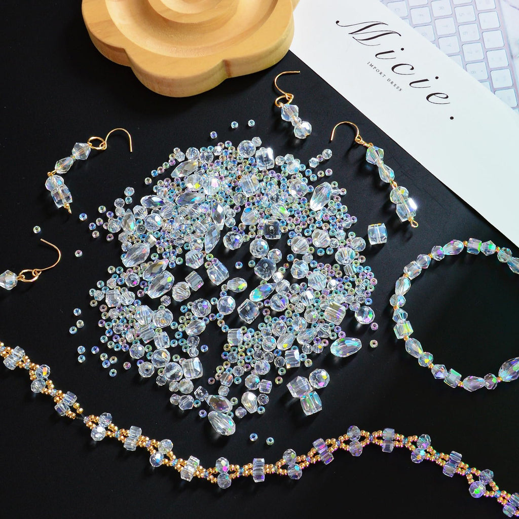 Assortment of clear crystal glass beads in various shapes and sizes, with finished jewelry pieces, on a black background.