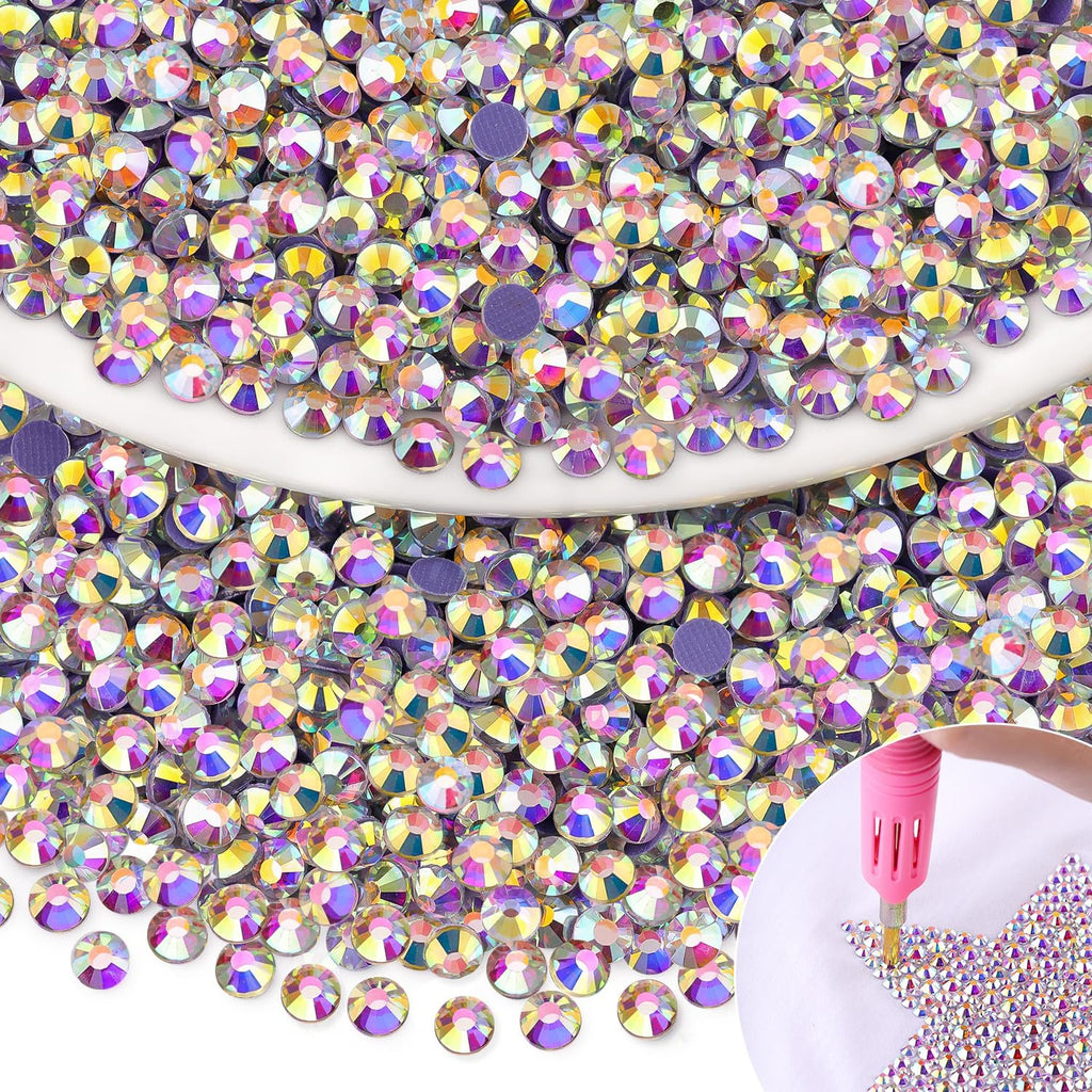 Pile of iridescent AB hotfix rhinestones with a pink applicator tool applying them to a surface in a star shape.