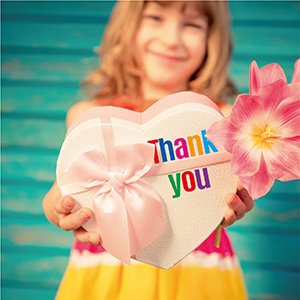 Smiling child holds a heart-shaped gift box with 'Thank You' stickers and a pink flower.