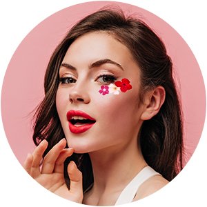 Woman with red lipstick and makeup wearing dried pressed flowers on her face