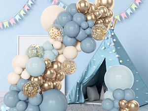 Dusty blue, white sand, and gold balloon arch with confetti balloons in a nursery setting with a teepee.