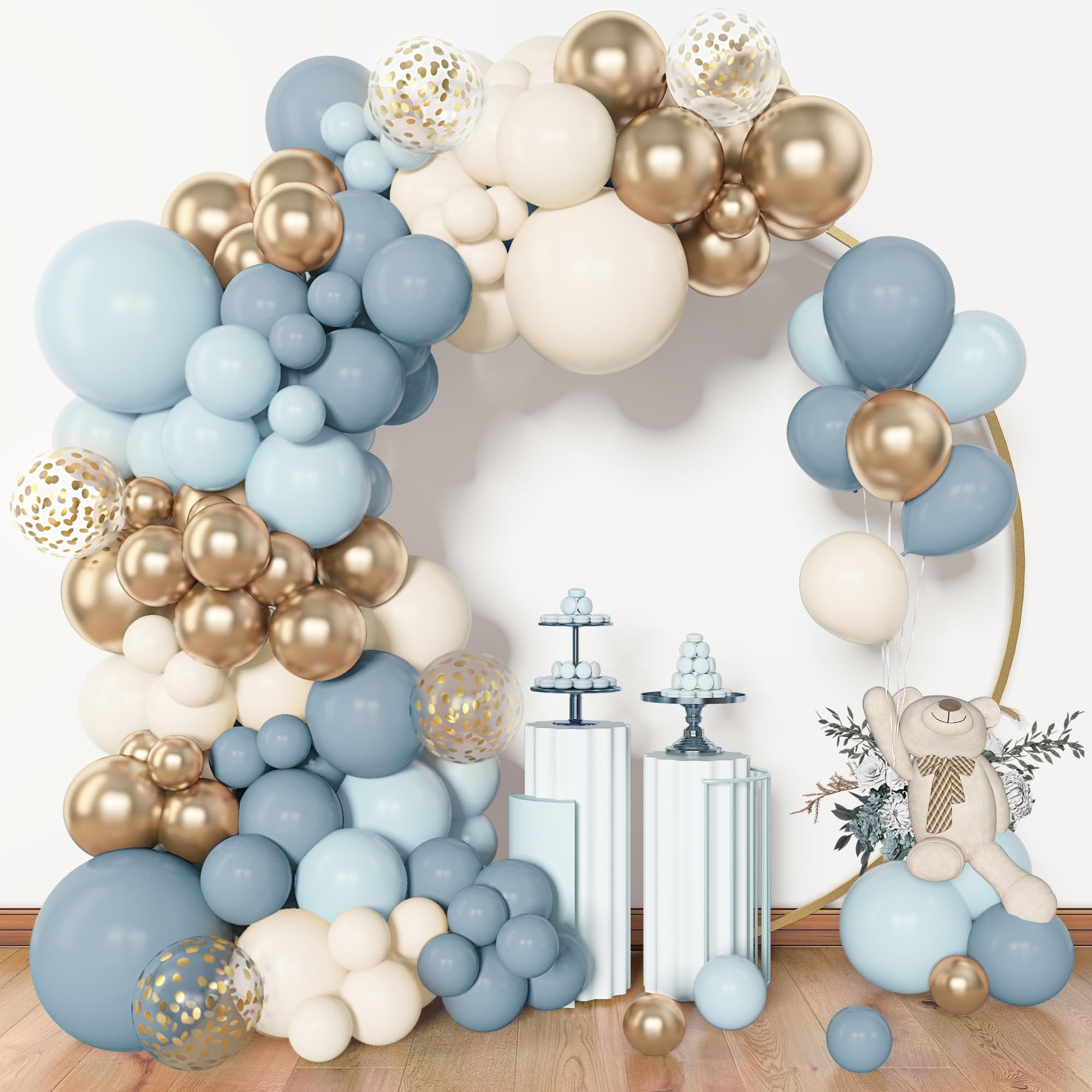 Dusty blue, white, and gold balloon arch with clear confetti balloons, a teddy bear, and dessert stands.