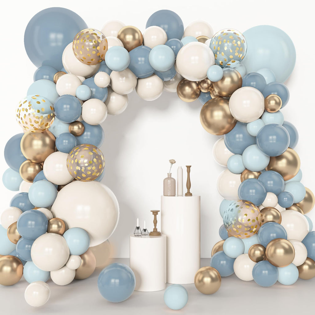 Dusty blue, white, and gold balloon arch with clear balloons featuring gold confetti, arranged around a white backdrop with pedestals.