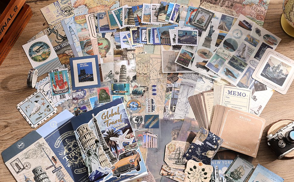 Scrapbook kit with travel-themed stickers, papers, notebook, and journaling supplies spread out on a wooden surface.