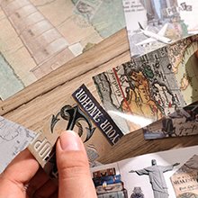 Close-up of travel-themed scrapbook supplies including stickers and papers with maps and landmarks.