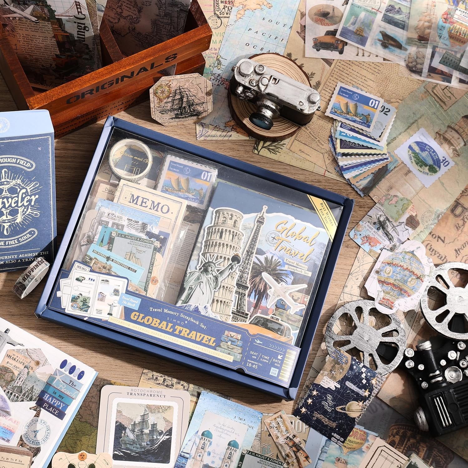 Travel-themed scrapbook kit contents laid out with decorative papers, stickers, notebook, and tape.