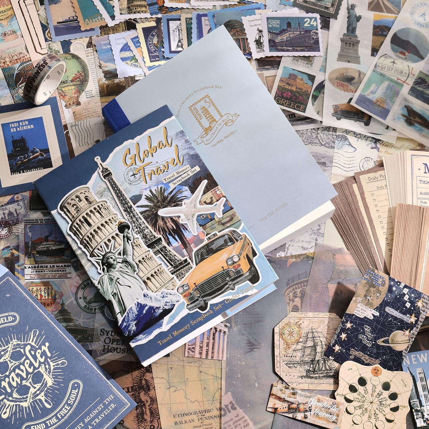 Travel-themed scrapbook supplies including notebooks, stickers, washi tape, and papers scattered on a surface.