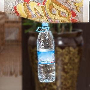 Diamond painting canvas with colorful pattern hanging above a plastic water bottle