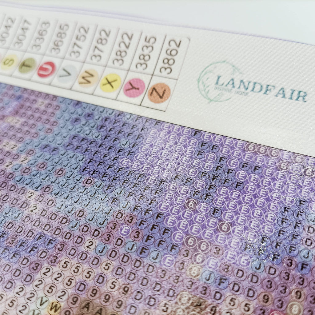 Diamond painting canvas detail showing color codes and symbols, with logo in the upper right corner.