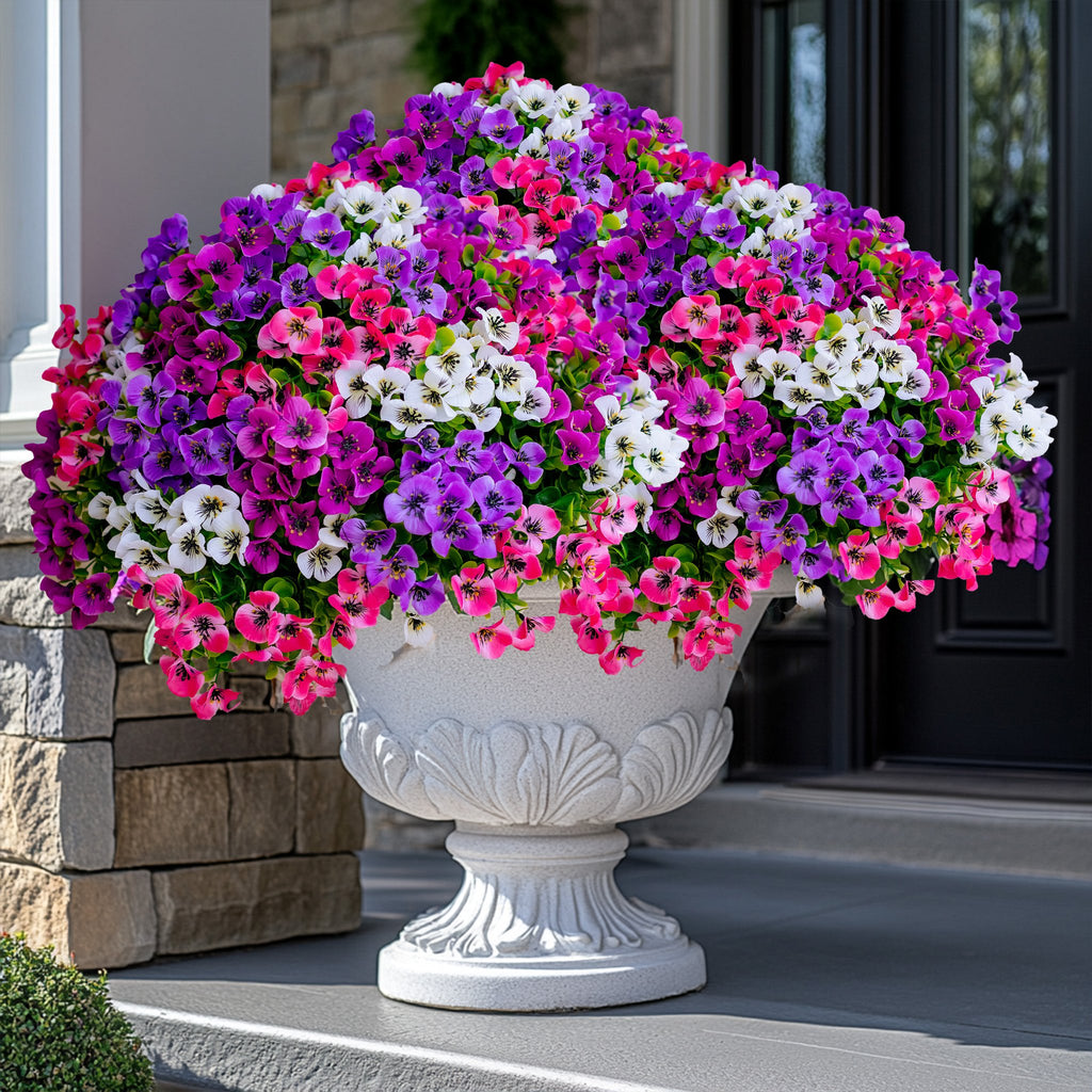 Artificial flowers in a decorative planter on a porch, featuring purple, pink, and white blooms.