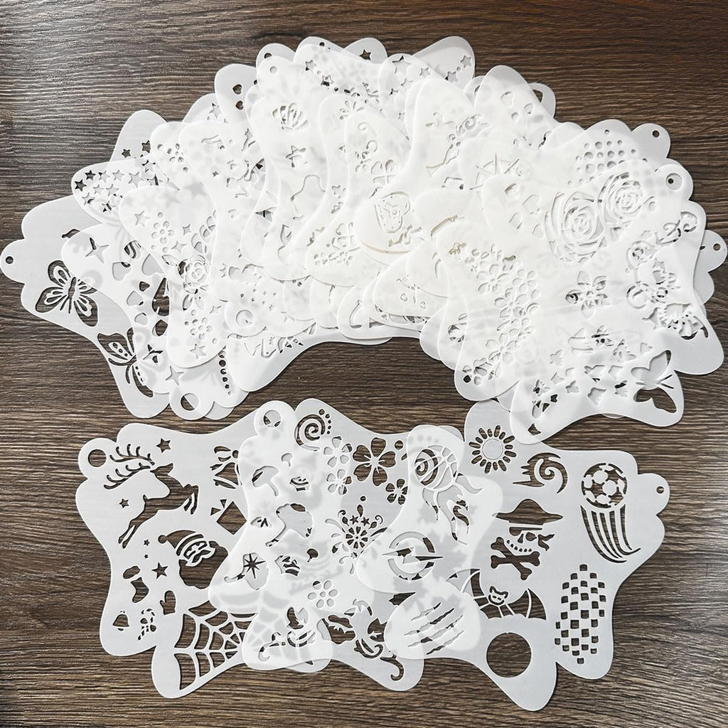 Collection of white face paint stencils with various patterns like butterflies, flowers, snowflakes, and skulls on a wooden background.