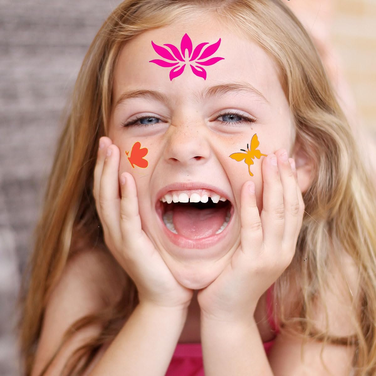 Young girl with face paint stencils of a pink lotus and orange butterflies laughing