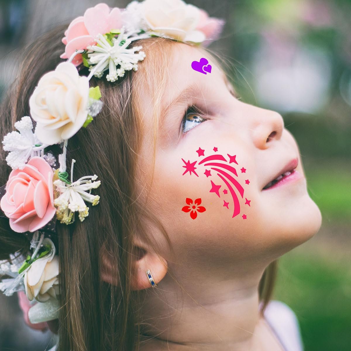 Close-up of a young girl wearing a floral crown and face paint stencils of stars, a flower, and hearts.